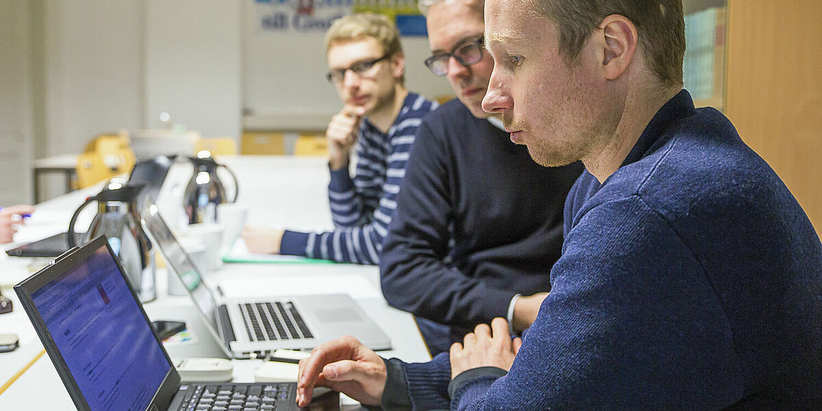 Symbolbild Forschung: Drei Herren arbeiten an einem Projekt.